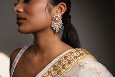 Dress up your outfits with our opulent Grey Nirvi Earrings. Handcrafted with high-quality Pachi Kundan, pearls and crystals on Gold plating, these earrings are a must-have in your jewelry box. Specifications Materials used: Pachi Kundan, pearls, crystals, Gold plating At Romikas, we pride ourselves on the craftsmanship and high quality of our jewelry, designed to enhance your natural beauty. Please contact us with any questions. Elegant Kundan Pearl Earrings With Stone Work, Elegant Pearl Earrings With Stone Work As Gift, Elegant Pearl Earrings With Stone Work For Gift, Elegant Pearl Drop Danglers For Reception, Elegant Pearl Meenakari Earrings For Diwali, Elegant Kundan Bridal Earrings With Stone Work, Elegant Kundan Bridal Earrings For Festive Occasions, Elegant Festive Jhumkas With Mirror Work, Elegant Pearl Earrings With Stone Work For Wedding