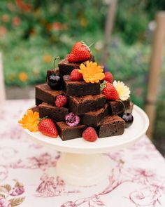 a cake that is sitting on top of a white plate with strawberries and raspberries