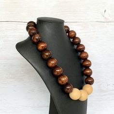 This chunky wood necklace was hand beaded using a mix of large 25mm round dark brown and 28mm round medium tone tan wooden beads in a modern color block design. The necklace measures 24 inches long and is securely fastened with a silver clasp.  Perfect for any gender!  Length can be adjusted if needed - just ask! Wood represents a sense of earthiness, spirituality, creativity, liberty, prosperity, health, and natural touch.  Perfect for meditation, prayer, yoga practices, and everyday wear!    C Brown Wooden Beads Round Jewelry, Brown Wooden Beads Jewelry, Brown Round Wooden Beads Jewelry, Handmade Brown Round Beaded Necklaces, Handmade Brown Beaded Necklaces, Brown Round Beaded Necklace With Large Beads, Brown Beaded Necklace With Large Round Beads, Wooden Brown Beaded Necklace Gift, Brown Wooden Beaded Necklace Gift