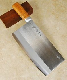 a large knife with a wooden handle on a counter top next to a cutting board