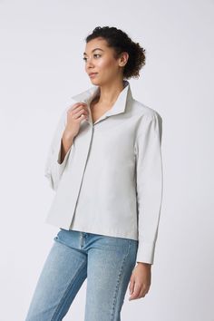 Meet the perfect transition style into the warmer days. Our Peggy Collared Shirt can be worn as a top or as a light outer layer. Made in our Italian Broadcloth, this style has a high collar with plenty of attitude, a drop shoulder fit, back pleat, and side slits for ease of wear. Drop shoulder fit, high stand collar, hidden button front placket, back yoke with inverted pleat, side slits on body - 51% Cotton, 49% Nylon - Fabric woven in Italy - Made in NYC - Dry clean or machine wash - Our model Fall Daywear Shirt With Spread Collar, Spread Collar Shirt For Daywear In Fall, Lapel Collar Shirt For Daywear In Fall, Fall Season Relaxed Fit Blouse For Layering, Versatile Relaxed Fit Blouse For Layering, Fall Tops With Lapel Collar And Placket, Fall Workwear Tops With Shirttail Hem, Fall Blouse With Shirttail Hem And Placket, Versatile Button-up Tops For Layering