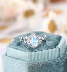 an engagement ring with a blue topaz sits on a velvet box