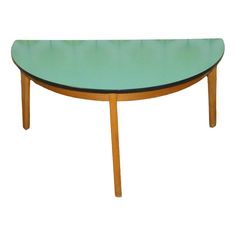 an oval table with wooden legs and a green glass top