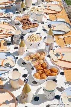 a long table with plates and cups filled with donuts on it's sides