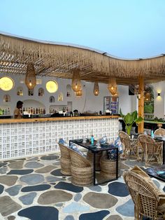 an outdoor bar with wicker chairs and tables under thatched umbrellas on the roof