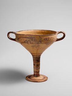 an old vase with writing on it is sitting on a table next to a gray background