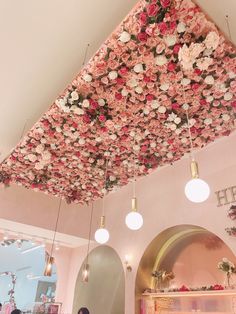 the ceiling is covered with pink flowers and hanging lights