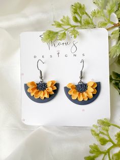 a pair of sunflower earrings on top of a white sheet