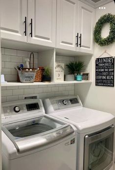 a washer and dryer in a laundry room with white cabinets on the wall