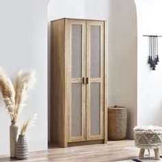 a tall wooden cabinet sitting next to a vase with dry grass in front of it