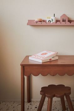 a wooden table with a book on top of it next to a small stool and shelf