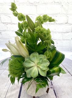 a white vase filled with green and white flowers