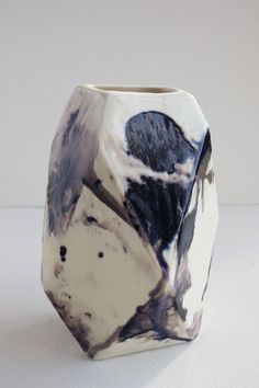 a black and white vase sitting on top of a table next to a white wall