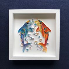 two colorful fish in a white frame on a blue wall with bubbles and water droplets