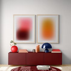 two paintings on the wall next to a red rug in a room with white walls