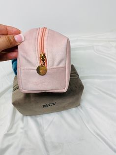 a pink purse sitting on top of a white bed next to a person's hand