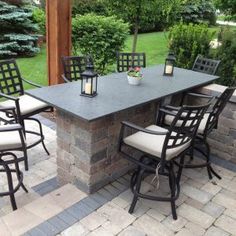 an outdoor dining table with chairs around it