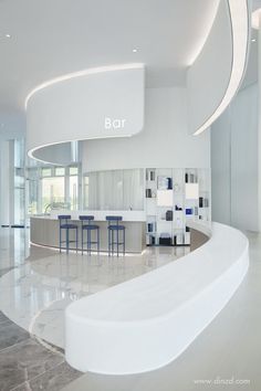 the interior of a modern bar with marble flooring and white walls, along with blue stools