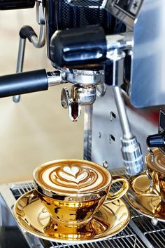 two golden coffee cups sitting next to each other on top of a saucer and stove