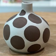 a brown and white vase sitting on top of a wooden table