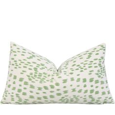 a green and white pillow with spots on it's side, in front of a white background