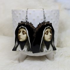 Double Sided Nun Head Earrings  ~ Measures approx. 2- inches ~ Made of lightweight Sublimation  ~ Laser cut and sublimated  ~ Stainless Steel ear wires ~ Hypoallergenic ~ Processing time is up to two weeks as all items are made to order.  May ship sooner if currently in stock. Thanks! follow us @iamsonotcoolvintage on instagram  save 10% :) Handmade Gothic Plug Earrings As Gift, Handmade Novelty Plug Earrings For Gift, Gothic Hoop Earrings As A Gift, Unique Plug Earrings As Gift, Unique Plug Earrings For Gift, Artistic Black Dangle Earrings, Artistic Black Nickel-free Earrings, Gothic Plug Earrings For Gifts, Dangle Earrings As Halloween Gift