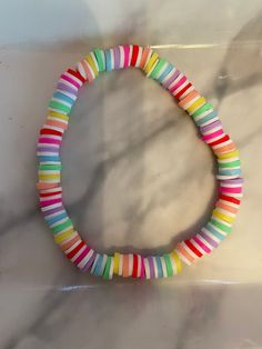 a multicolored bracelet is displayed on a marble countertop in the shape of a circle