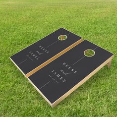 two black and gold cornhole game boards sitting on top of a green grass covered field