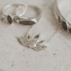 Solidified cremains set in the 5mm circular setting on this stunning and unique .925 Sterling Silver Lotus Flower Cutout Necklace with fixed bails on each side that attach to the chain and an overall size of 24x16mm. The Lotus is a symbol of the beauty that can grow from even the darkest of places, and thus, the love t White Gold Spiritual Necklace With Gemstone, Spiritual White Gold Gemstone Necklace, Elegant Flower Pendant Necklace For Meditation, Delicate Sterling Silver Birth Flower Necklaces, Spiritual Sterling Silver Jewelry With Birth Flower, Sterling Silver Nature-inspired Necklace For Anniversary, Nature-inspired Sterling Silver Necklace For Anniversary, Spiritual White Gold Jewelry Gift For Her, Spiritual White Gold Necklace For Meditation