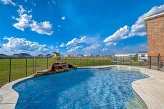 a backyard with a swimming pool and fenced in area next to the grass field