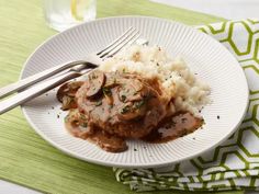 a white plate topped with meat and mushrooms covered in gravy