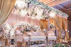 an elaborately decorated stage set up for a wedding ceremony with flowers and chandeliers