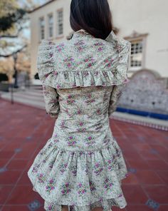 Saddle up in style with the Quinlynn Taupe Floral Ruffle Bow Dress. This versatile dress is perfect for any occasion, whether you're hitting the rodeo in your cowgirl boots or stepping out in the spring sun with wedges. With its playful ruffle and bow details, you'll be the talk of the town. Giddy up and grab yours today! Product Details: Features: Adjustable bow tie. Ruffle details. Side zipper closure. Fit: True to size. Model is 5'3 and wearing a size small. Fabric: 100% cotton; Lining- 100% Fitted Mini Dress With Ruffles For Garden Party, Cotton Ruffle Mini Dress Fitted, Fitted Cotton Mini Dress With Ruffles, Fitted Dress With Ruffled Skirt For Garden Party, Fitted Flirty Mini Dress For Spring, Fitted Spring Dress With Ruffled Skirt, Feminine Ruffle Sleeve Dresses For Fall, Summer Garden Party Dress With Ruffled Collar, Spring Fitted Dress With Ruffle Hem