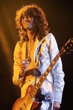 a man with long hair playing an electric guitar