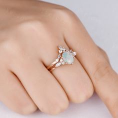 a woman's hand wearing a ring with an opal and diamonds on it