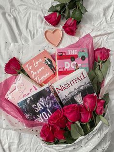 roses and books in a white basket on a bed with pink tissue, heart shaped brooch