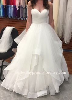 a woman standing in front of a rack of dresses