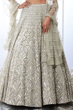 Silver lehenga featuring platinum cut sequin and crystal embellishment in cascade motif pattern. Paired with criss-cross back and fully embroidered net dupatta.
Component: 3
Pattern: Embroidered
Type Of Work: Crystal, Sequin
Neckline: Plunge V-neck
Sleeve Type: Sleeveless
Fabric: Net
Color: Silver
Other Details: 
Cascade motif embroidery
Criss-cross back blouse
Occasion: Wedding - Aza Fashions Glamorous Floor-length Choli With Resham Embroidery, Silver Hand Embellished Sharara For Reception, Festive Silver Hand Embellished Dress, Glamorous Resham Embroidered Choli For Wedding, Glamorous Anarkali Set With Intricate Embroidery For Reception, Glamorous Wedding Choli With Resham Embroidery, Silver Hand Embellished Dresses For Festive Occasions, Glamorous Floor-length Sets With Intricate Embroidery, Silver Anarkali Style Hand Embellished Sharara