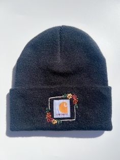 a black beanie with the logo of a car on it and flowers around the brim