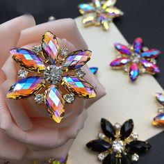 a flower shaped brooch sitting on top of a table next to other jewelries