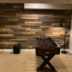 a foosball table sitting in front of a wall with wooden planks on it