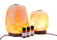 three bottles of essential oils sit next to an orange himalayan salt lamp with the light turned on