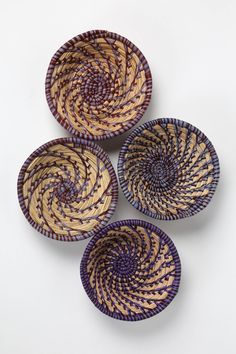 three woven baskets sitting next to each other on a white surface with purple and yellow designs