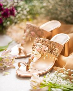 a pair of gold sandals with flowers on them