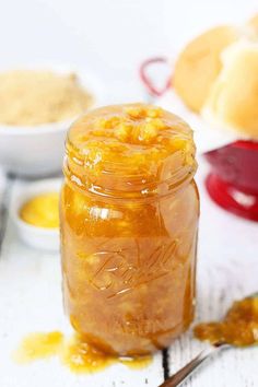 a glass jar filled with food sitting on top of a white table next to bread