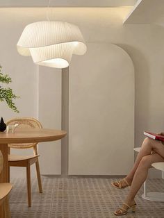 a woman sitting at a table with a book in her hand and a potted plant next to her