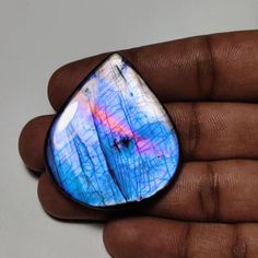 a hand holding a blue and white tear shaped glass object in it's palm