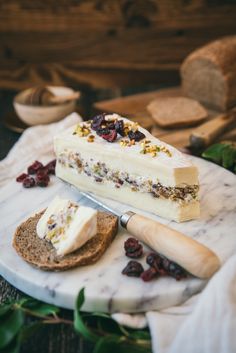 a piece of cake sitting on top of a white plate next to bread and cranberries