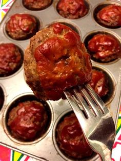 a fork is holding up a meatloaf muffin in a muffin tin