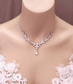 a close up of a woman's breast wearing a necklace with pearls on it